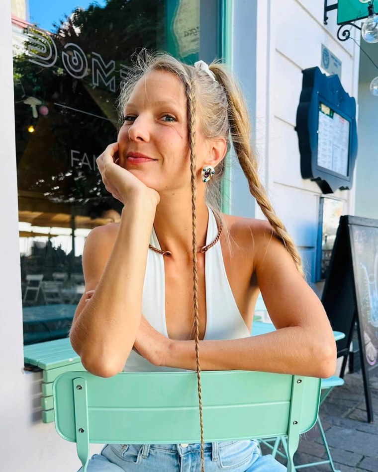 Slava sitting at a cafe table, chin resting on her hand.